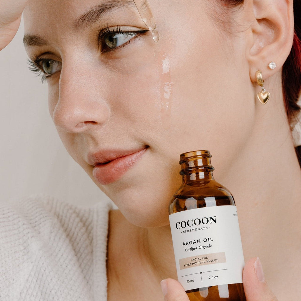 Oh Canada Gifts model applying lightweight organic Argan Facial Oil to her cheek for deep skin nourishment
