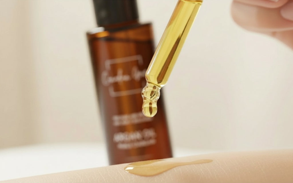 Oh Canada Gifts organic argan oil dropper applying golden oil to skin with amber bottle in background