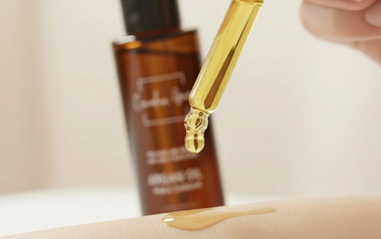 Oh Canada Gifts organic argan oil dropper applying golden oil to skin with amber bottle in background