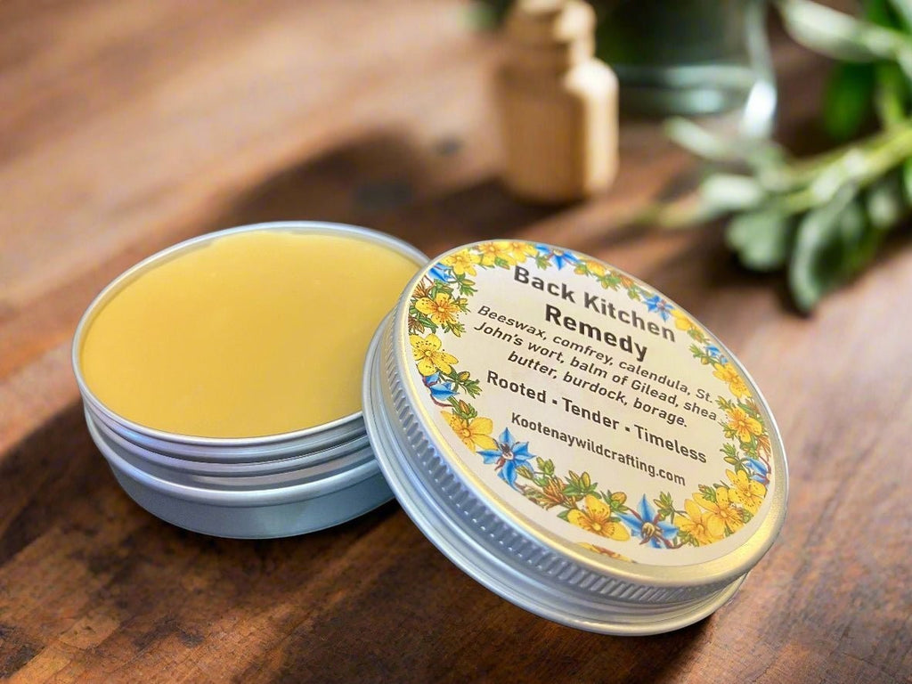 Oh Canada Gifts Back Kitchen Heritage Salve in a round metal tin with botanical label on a rustic wooden surface.