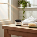 Oh Canada Gifts Cocoon Apothecary Bay Rum styling pomade jar on a wooden table with white towels and a hairbrush.