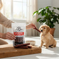 Oh Canada Gifts beef tripe sticks being offered to a golden retriever puppy in a bright, sunlit home setting.