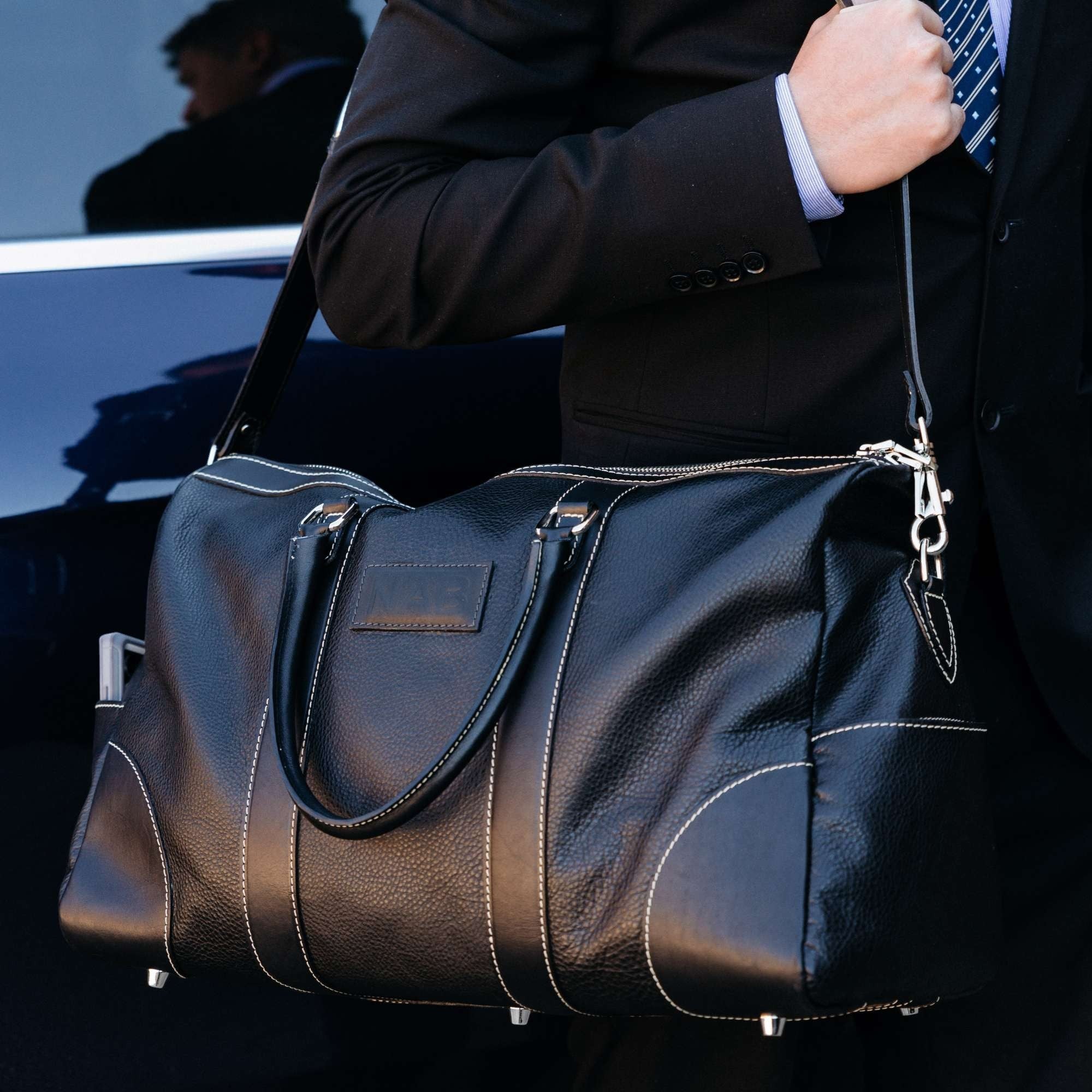 Oh Canada Gifts Shield Duffle bag in black full-grain leather carried by a man in a suit
