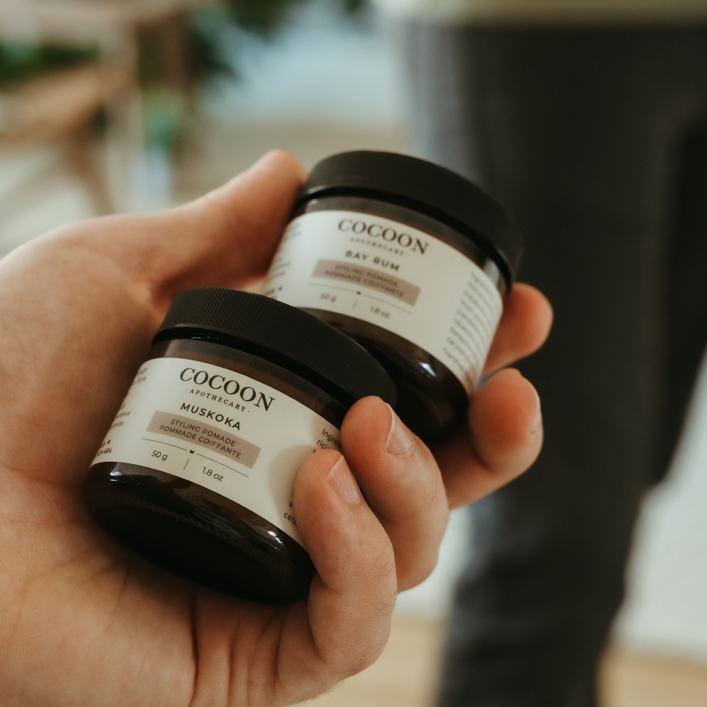 Oh Canada Gifts Cocoon Apothecary Bay Rum and Muskoka styling pomade jars held in a hand