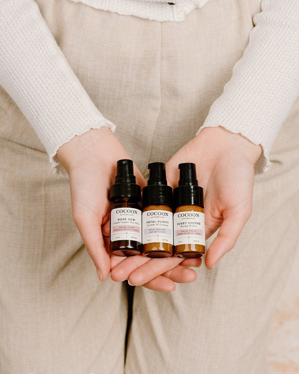 Oh Canada Gifts Cocoon Apothecary travel-size skincare kit with cleanser, toner, and cream in amber glass bottles.