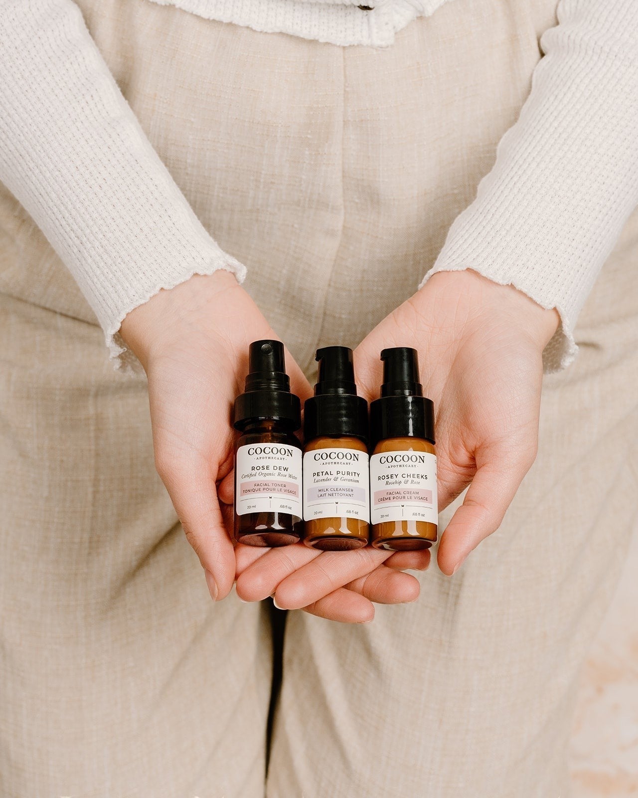 Oh Canada Gifts Cocoon Apothecary travel-size skincare kit with cleanser, toner, and cream in amber glass bottles.
