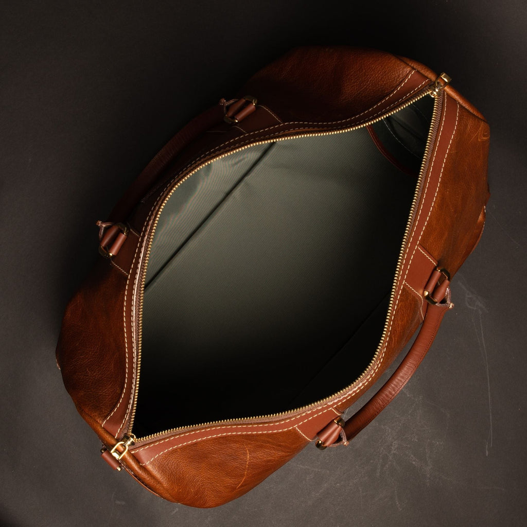Oh Canada Gifts Shield Duffle bag in cognac full-grain leather with open top and gold zipper hardware