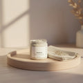 Oh Canada Gifts Polish It creamy exfoliant in a clear jar on a wooden tray with a cloth, featuring botanical texture.