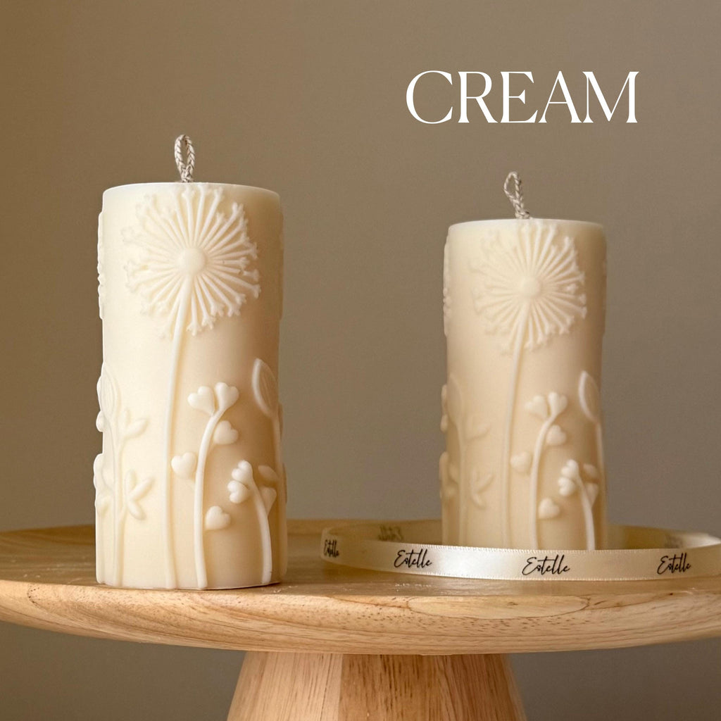 Oh Canada Gifts cream soy wax pillar candles with embossed dandelion botanical motifs on a wooden pedestal stand.