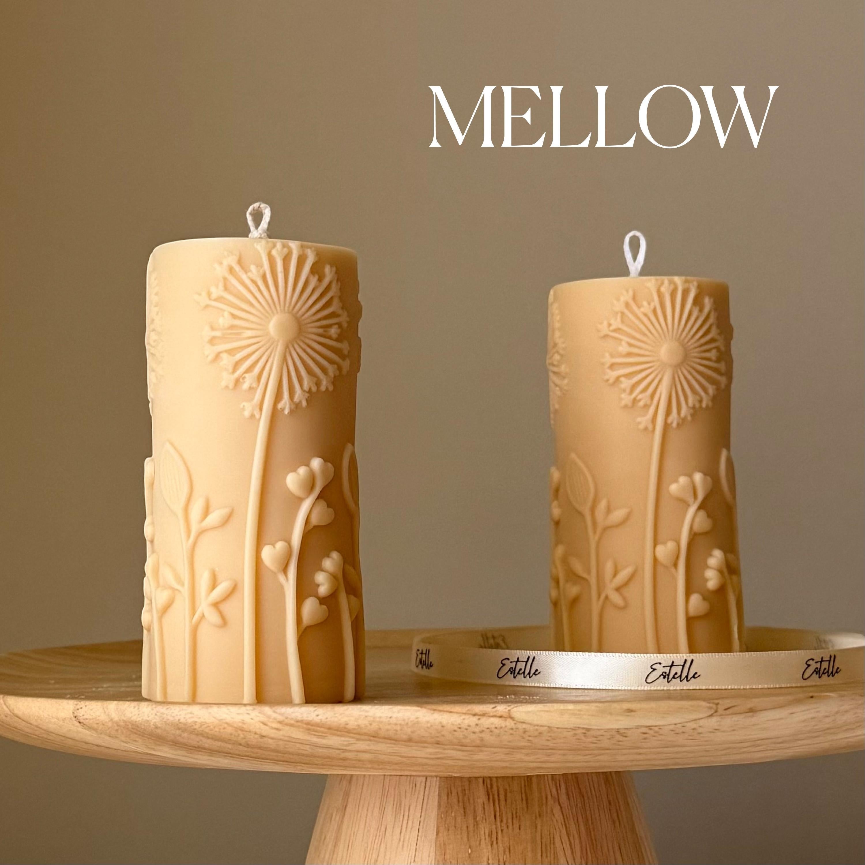Oh Canada Gifts dandelion-motif sculptural soy wax pillar candles in beige on a wooden pedestal stand.