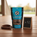 Oh Canada Gifts bulk case of 12 bags of natural dried sardine pet treats on a wooden deck with a leather leash