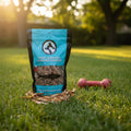 Oh Canada Gifts dried sardine dog and cat treats in a bag with a red toy on grass in a sunlit park