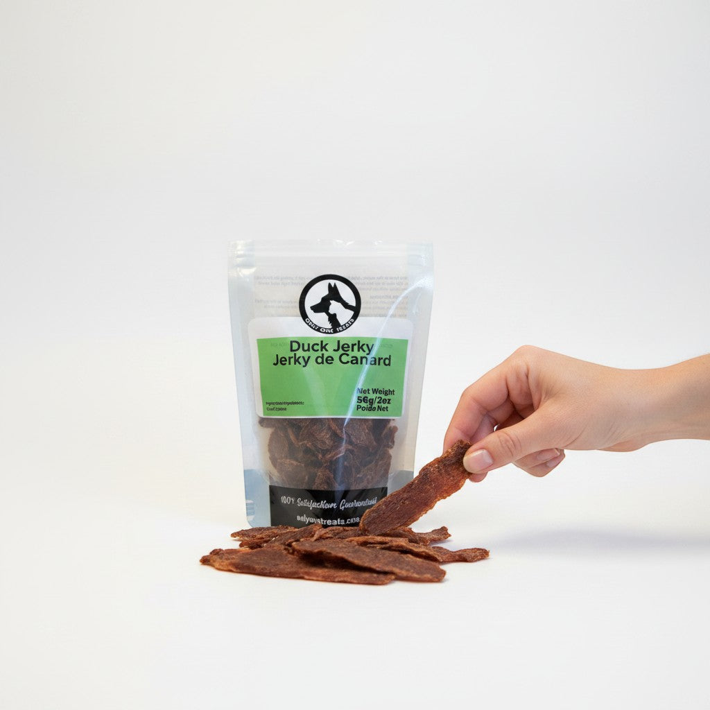 Oh Canada Gifts duck jerky treat for dogs in a 56g bag, held by a hand against a white background.