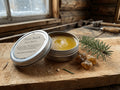 Oh Canada Gifts Fire Balm pain salve in a metal tin with natural resin and pine needle on a rustic wooden surface.