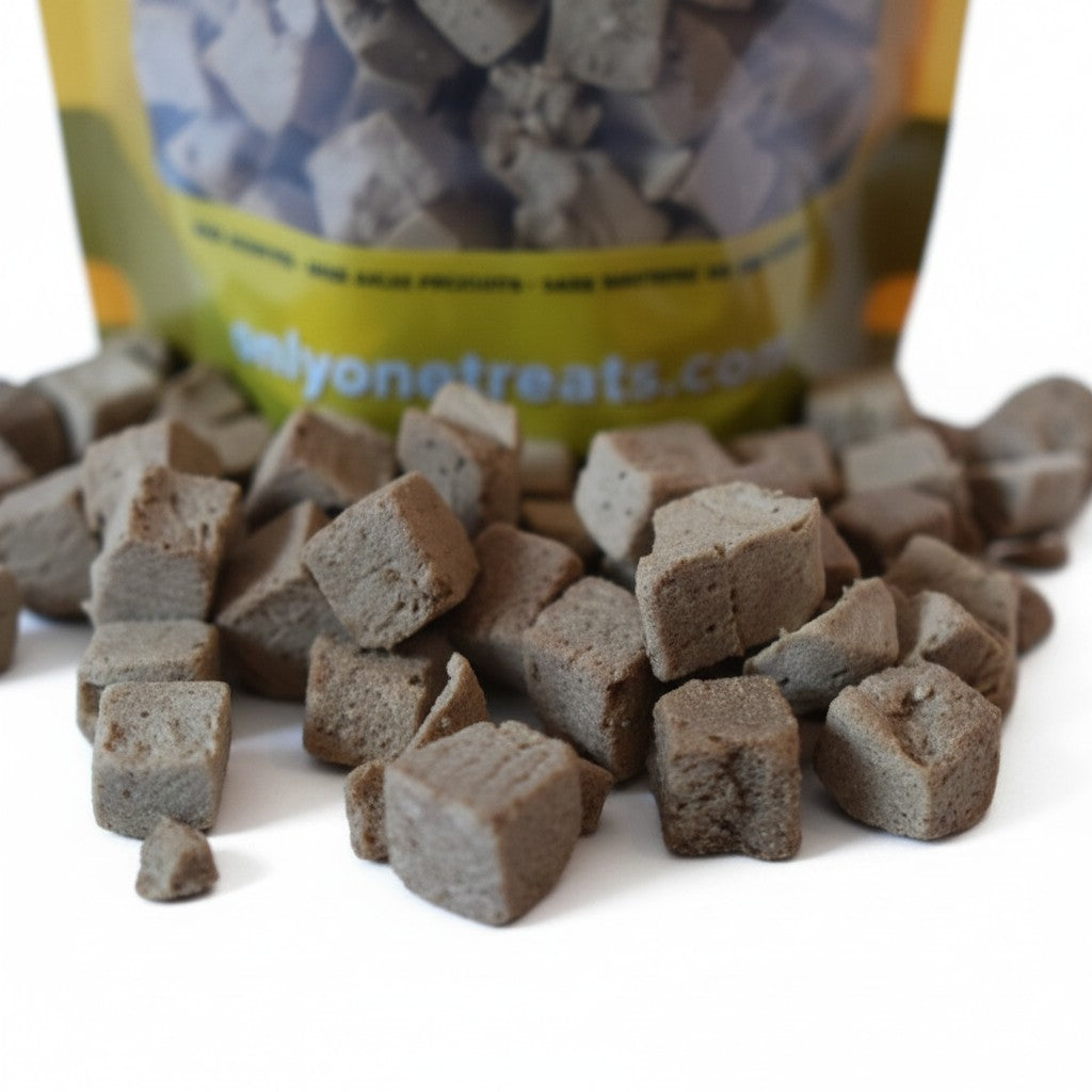 Oh Canada Gifts freeze-dried chicken treats for dogs and cats in a small pile with the product bag in the background.
