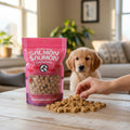 Oh Canada Gifts freeze-dried salmon treats in a pink bag with a puppy watching a hand offer a piece on a table