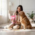 Oh Canada Gifts freeze-dried salmon treat bag held by a woman sitting on a rug with her golden retriever dog