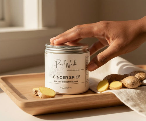 Oh Canada Gifts Ginger Spice whipped body butter in a glass jar on a wooden tray with fresh ginger slices.