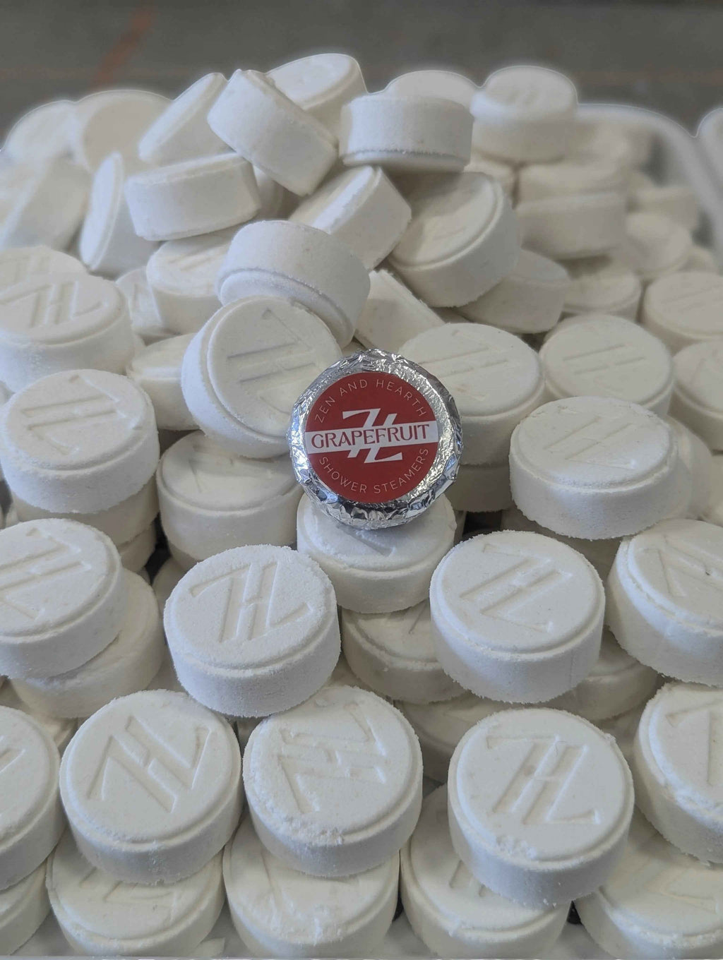 Oh Canada Gifts Zen & Hearth grapefruit shower steamers, white aromatherapy tablets with embossed logo in a pile.