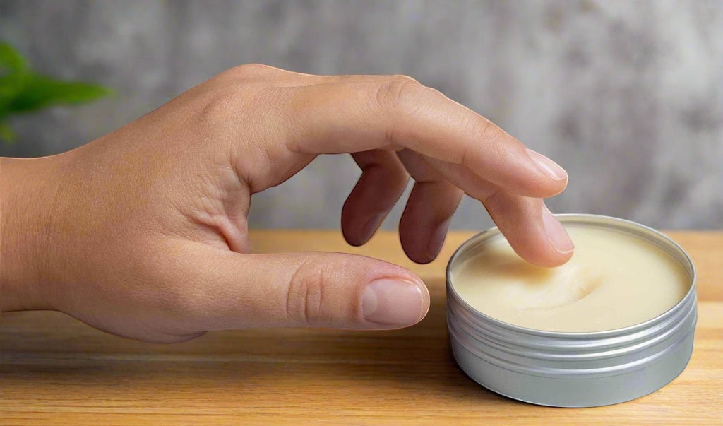 Oh Canada Gifts pure grass-fed Canadian tallow balm in a metal tin being applied by a finger on a wooden surface.