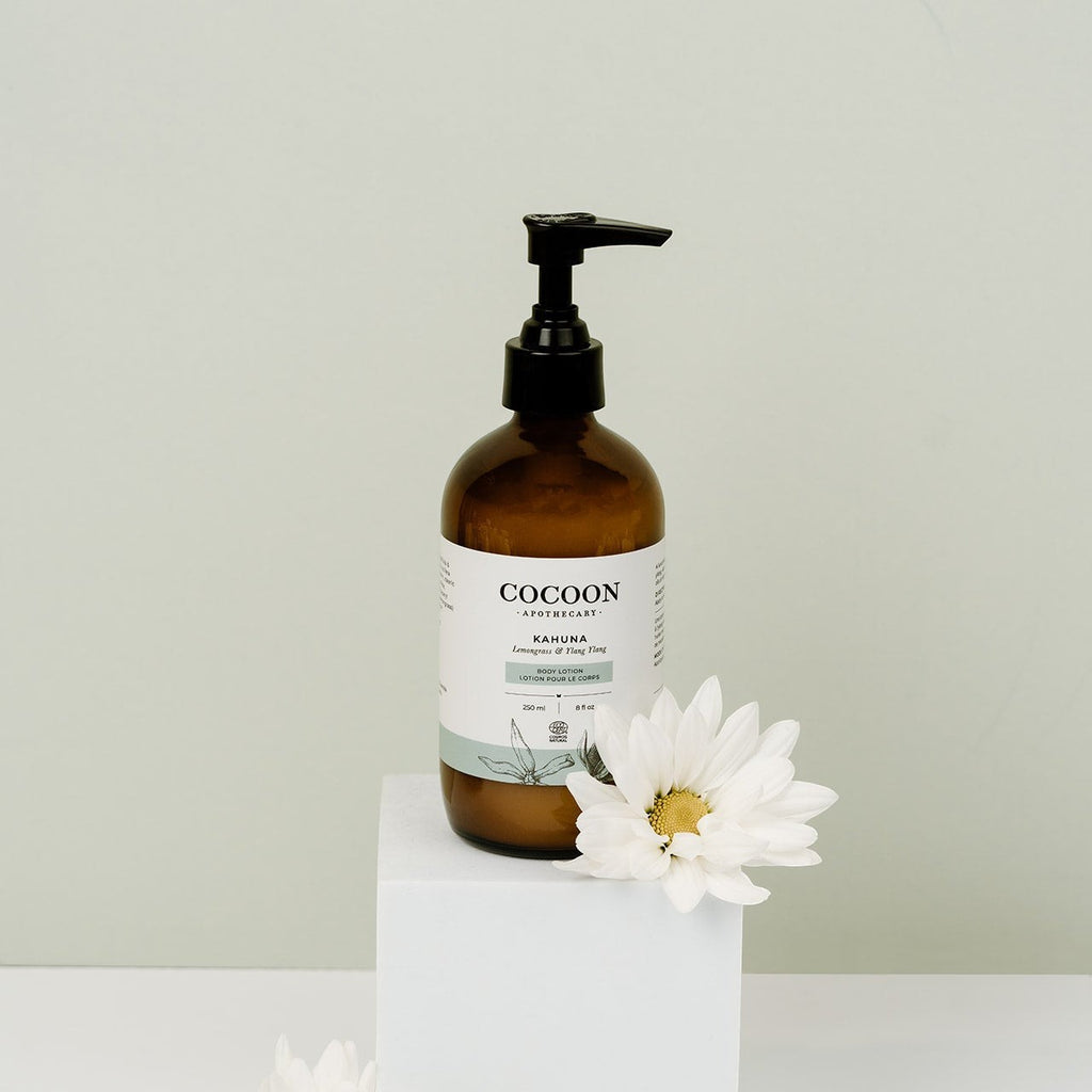 Oh Canada Gifts Cocoon Apothecary Kahuna body lotion in an amber glass pump bottle with a white flower on a pedestal.