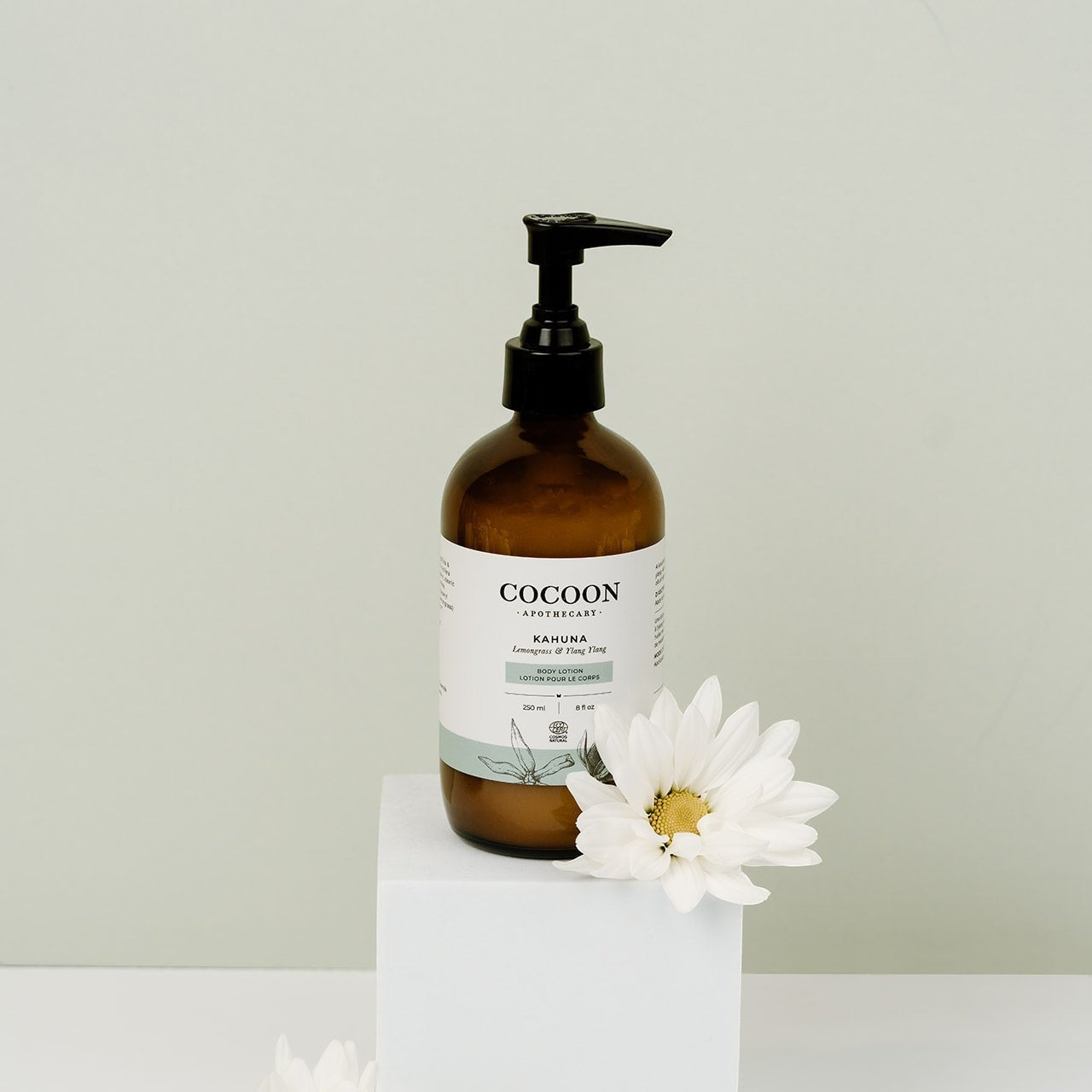Oh Canada Gifts Cocoon Apothecary Kahuna body lotion in an amber glass pump bottle with a white flower on a pedestal.