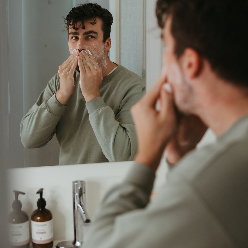 Oh Canada Gifts Malechemy facial cleanser being applied by a man in a bathroom mirror reflection