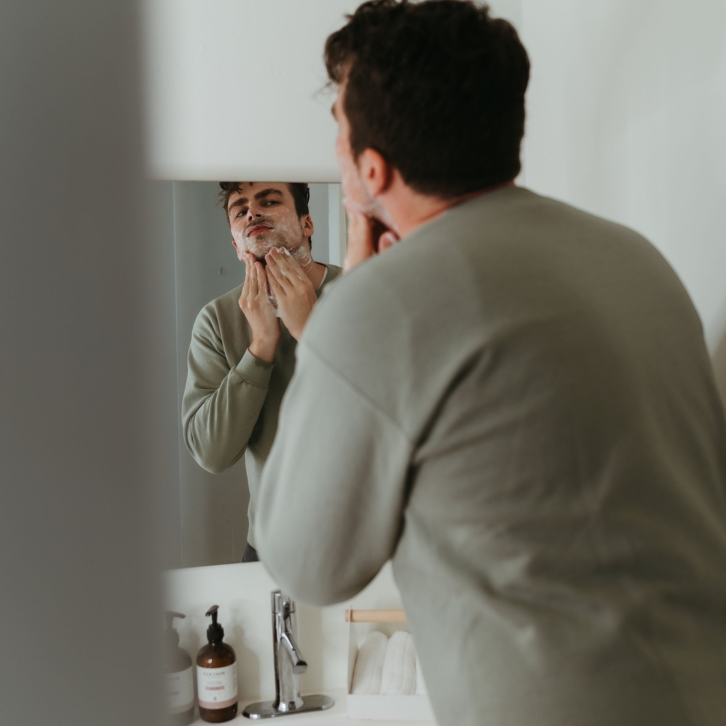 Oh Canada Gifts Malechemy plant-based shaving cream applied to a man's face in a bathroom mirror reflection