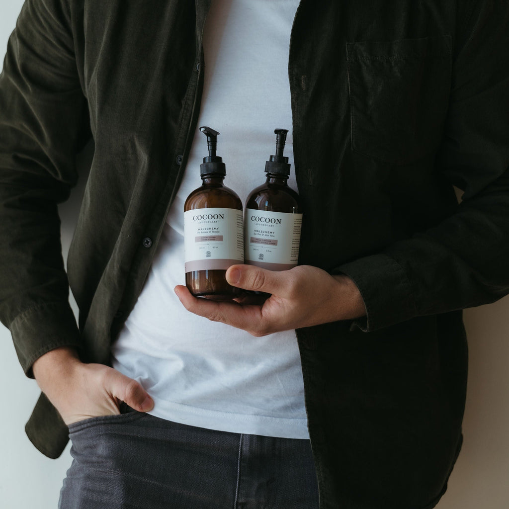 Oh Canada Gifts Malechemy shaving cream bottles held by a man wearing a dark green shirt and white t-shirt.
