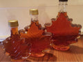 Oh Canada Gifts organic maple syrup in three iconic maple leaf-shaped glass bottles of varying sizes.