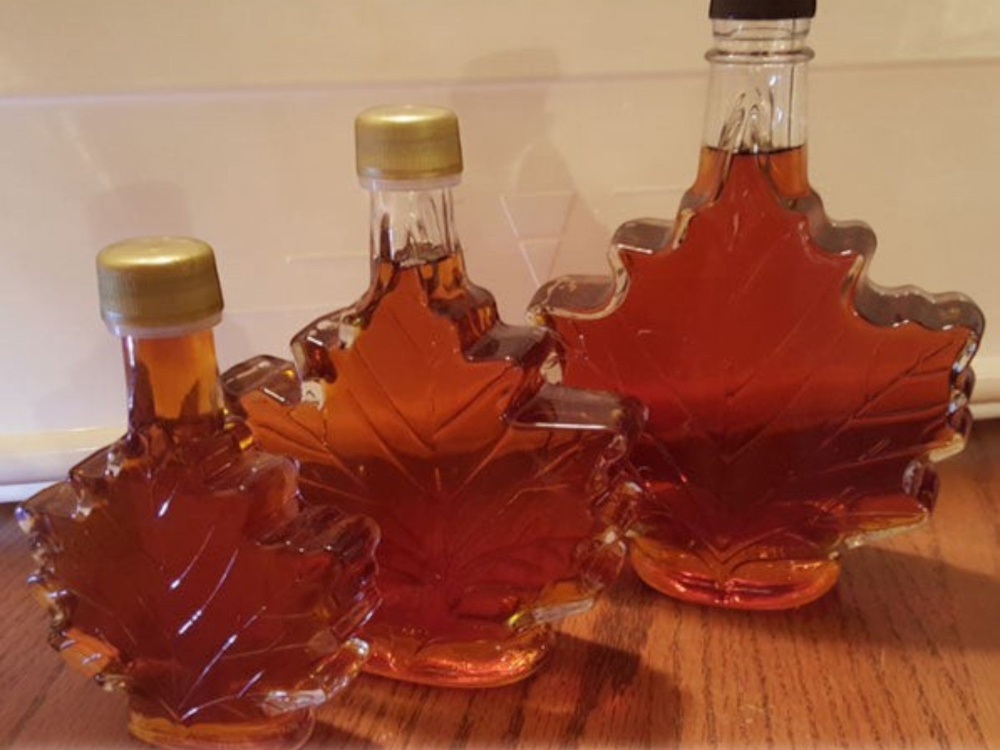 Oh Canada Gifts organic maple syrup in three iconic maple leaf-shaped glass bottles of varying sizes.