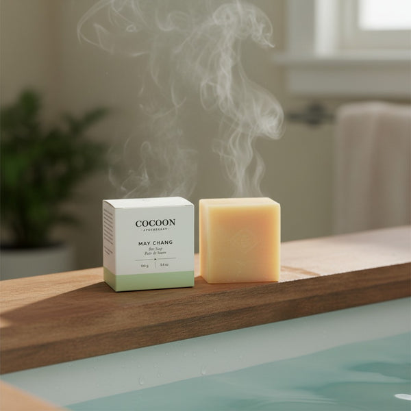 Oh Canada Gifts Cocoon Apothecary May Chang bar soap with its packaging on a wooden bathtub edge with steam rising.
