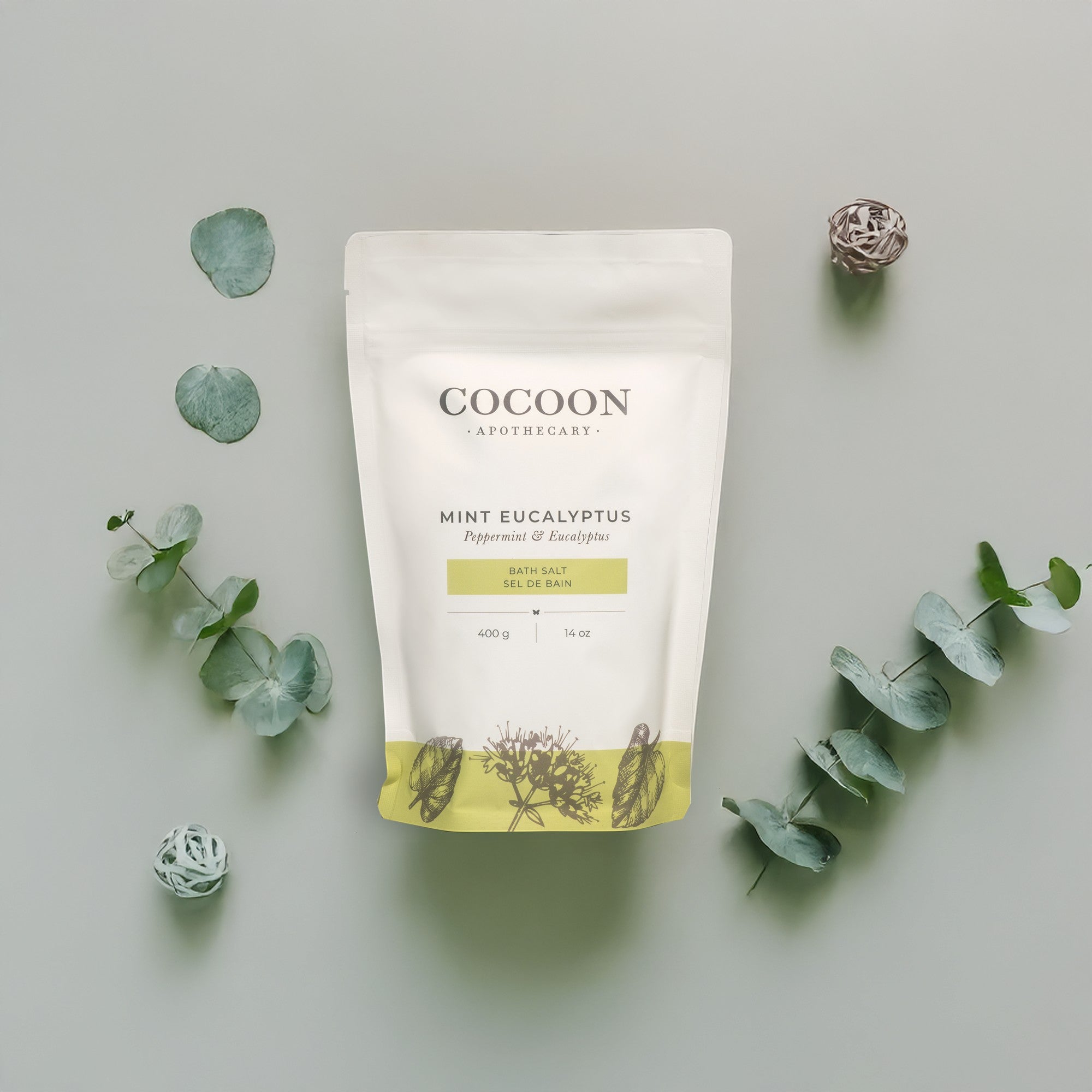 Oh Canada Gifts Cocoon Apothecary mint eucalyptus bath salts in a white pouch surrounded by eucalyptus leaves
