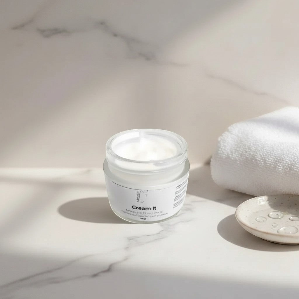 Oh Canada Gifts Cream It nourishing whipped facial moisturizer in a glass jar on a marble surface with a white towel.