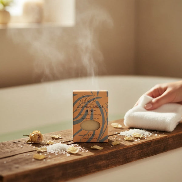 Oh Canada Gifts oatmeal milk and honey soap bar in packaging on a wooden tray with steam in a relaxing bathroom setting.