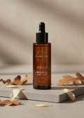 Oh Canada Gifts organic cold-pressed argan oil in an amber glass dropper bottle on a stone base with autumn leaves.