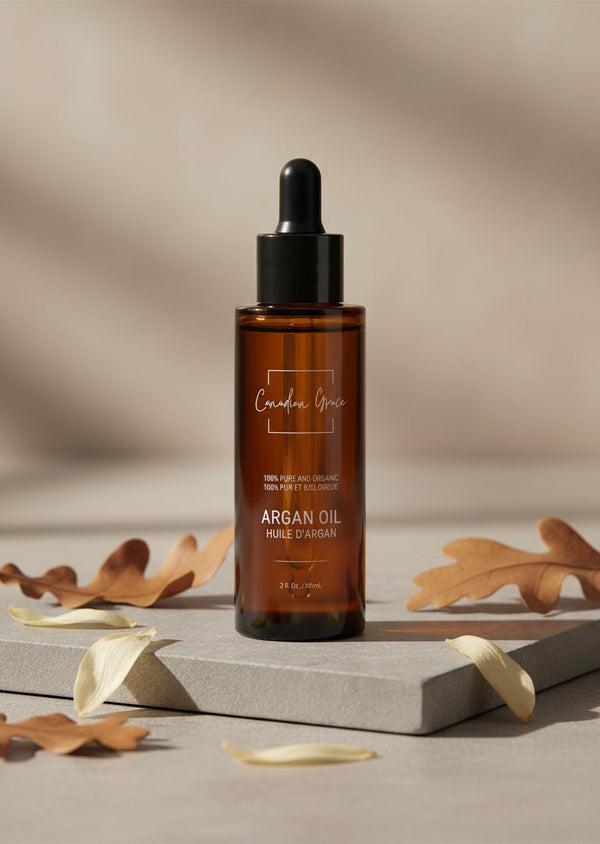 Oh Canada Gifts organic cold-pressed argan oil in an amber glass dropper bottle on a stone base with autumn leaves.