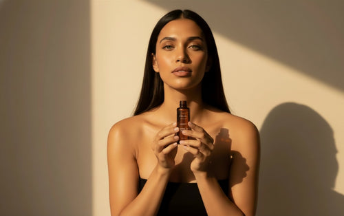 A woman holding a bottle of Oh Canada Gifts Canadian Grace 100% organic cold-pressed jojoba oil in warm sunlight.