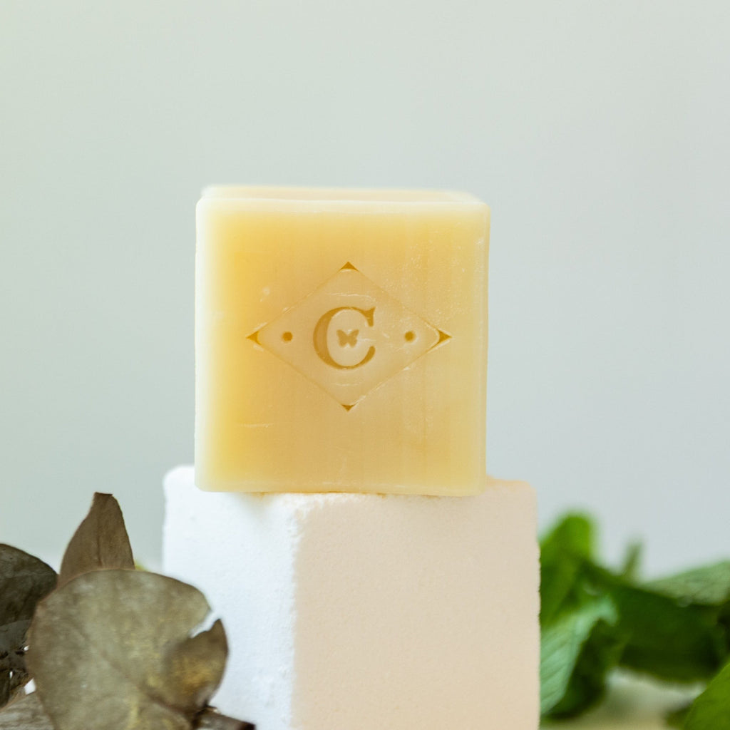 Oh Canada Gifts Cocoon Apothecary handcrafted patchouli bar soap with embossed logo on a white block with greenery