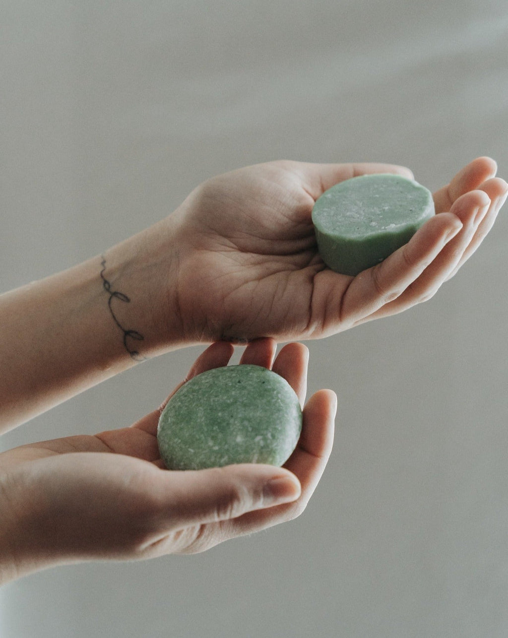 Oh Canada Gifts peppermint and eucalyptus zero-waste shampoo bars held in hands, showing a light green solid texture.