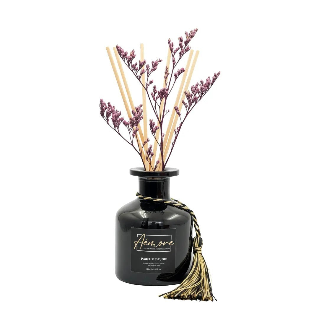 Oh Canada Gifts Parfum de Joie reed diffuser in a black glass bottle with rattan reeds and a preserved flower.