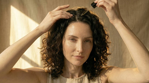 Oh Canada Gifts model applying Canadian Grace rosemary and castor hair oil with a dropper to her curly hair scalp