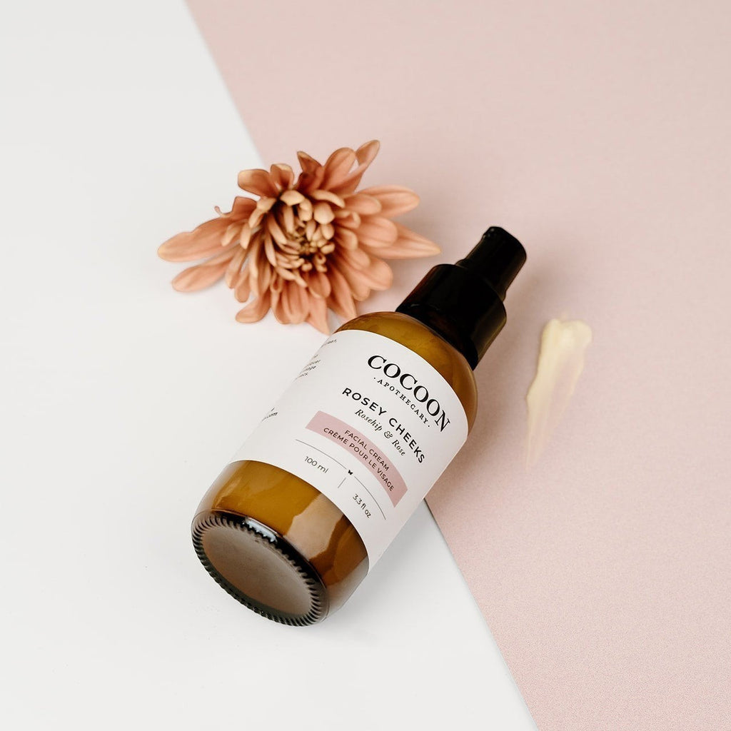 Oh Canada Gifts Rosey Cheeks facial cream in an amber glass bottle with a pump, featuring rosehip and shea butter.