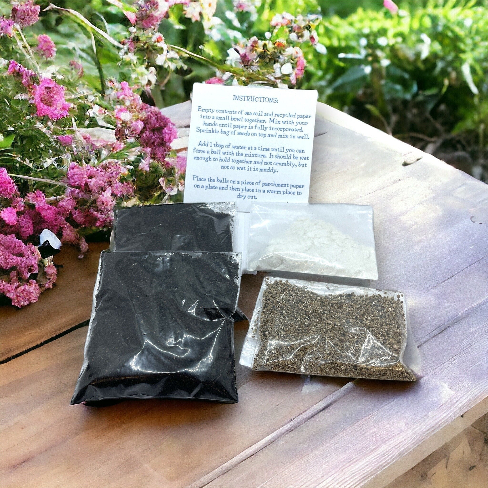 Oh Canada Gifts DIY seed bomb kit with individually packaged soil, paper, and wildflower seeds on a wooden surface.