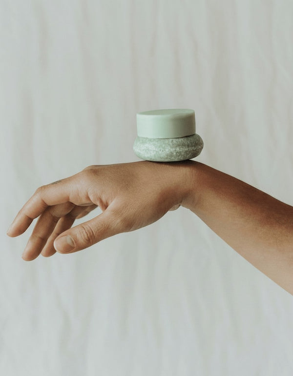 Oh Canada Gifts zero-waste shampoo and conditioner bar duo balanced on a hand, featuring natural botanical ingredients.