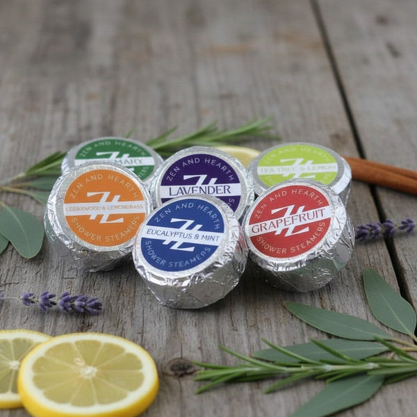 Oh Canada Gifts Zen & Hearth shower steamers in foil wrappers with various scent labels on a rustic wooden surface.