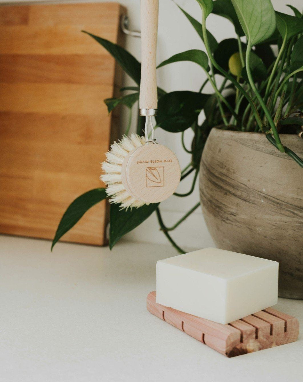 Oh Canada Gifts solid dish soap bar on a cedar tray with a wooden dish brush in a bright kitchen setting.