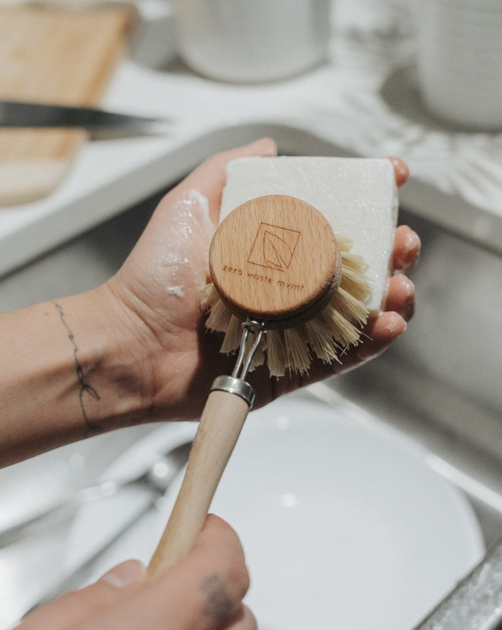 Oh Canada Gifts Bergamot and Lime solid dish soap bar being lathered with a wooden dish brush in a kitchen sink