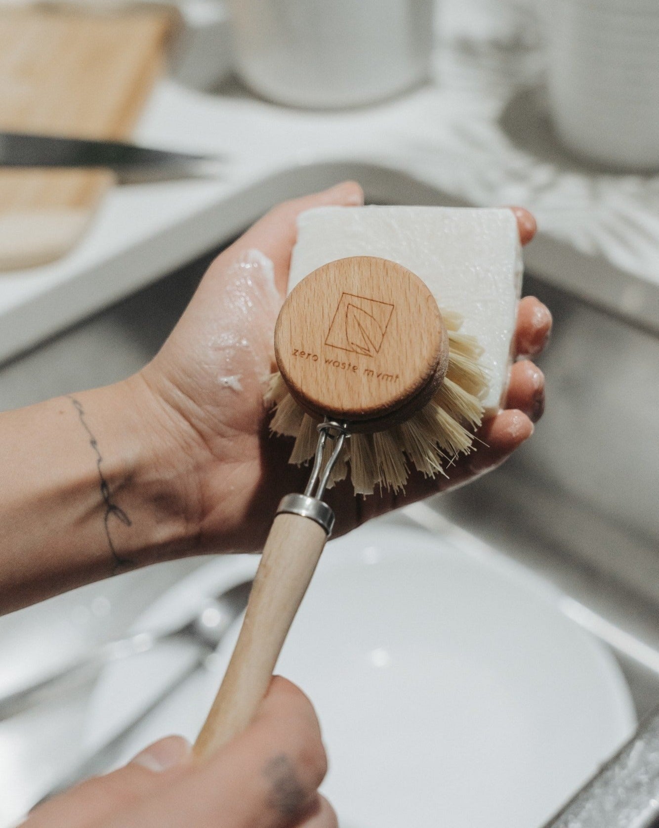 Oh Canada Gifts Bergamot and Lime solid dish soap bar being lathered with a wooden dish brush in a kitchen sink