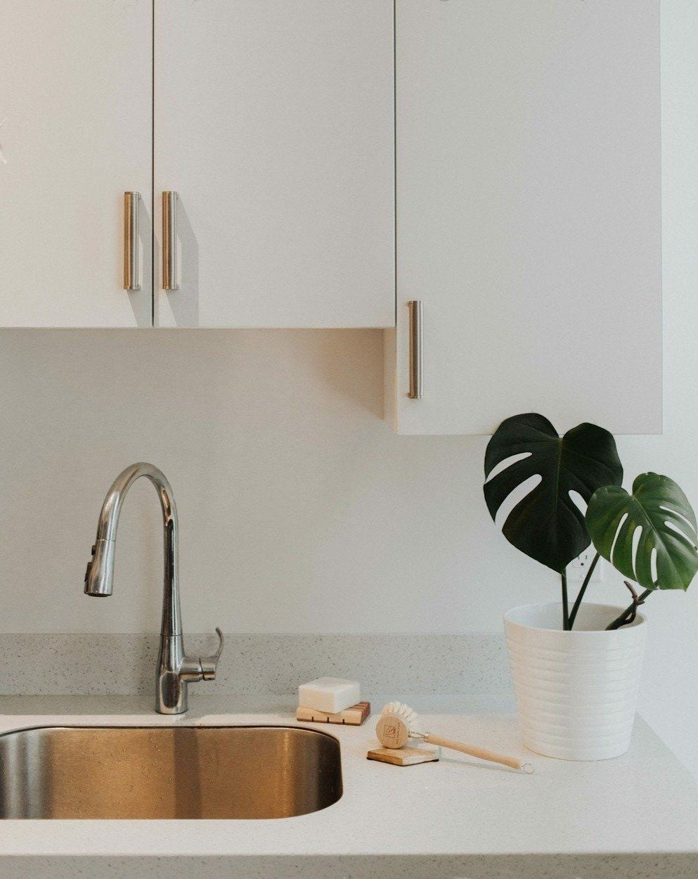 Oh Canada Gifts solid dish soap bar on a wooden tray next to a dish brush by a modern kitchen sink.